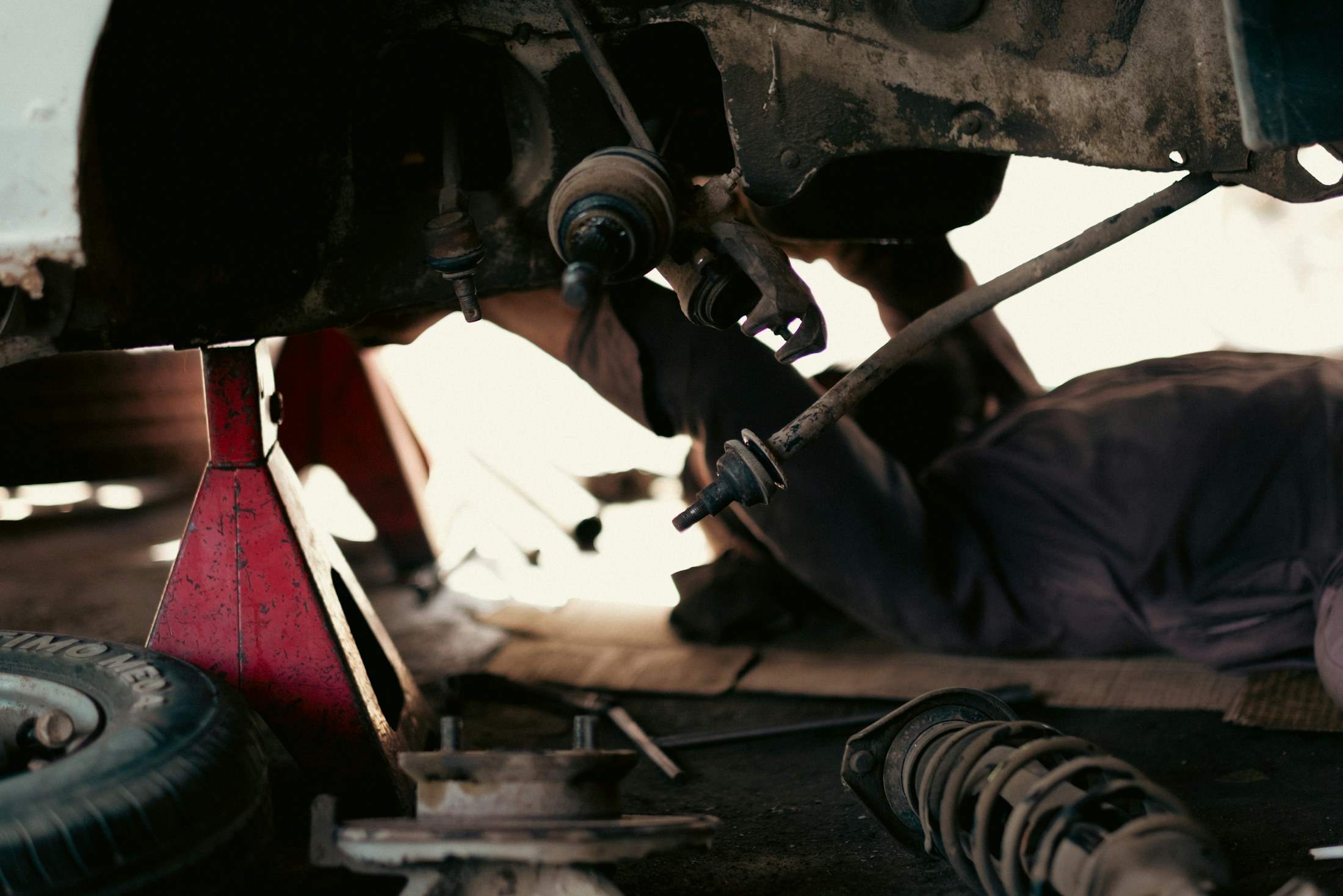 Mechanic working beneath a raised vehicle in an auto shop